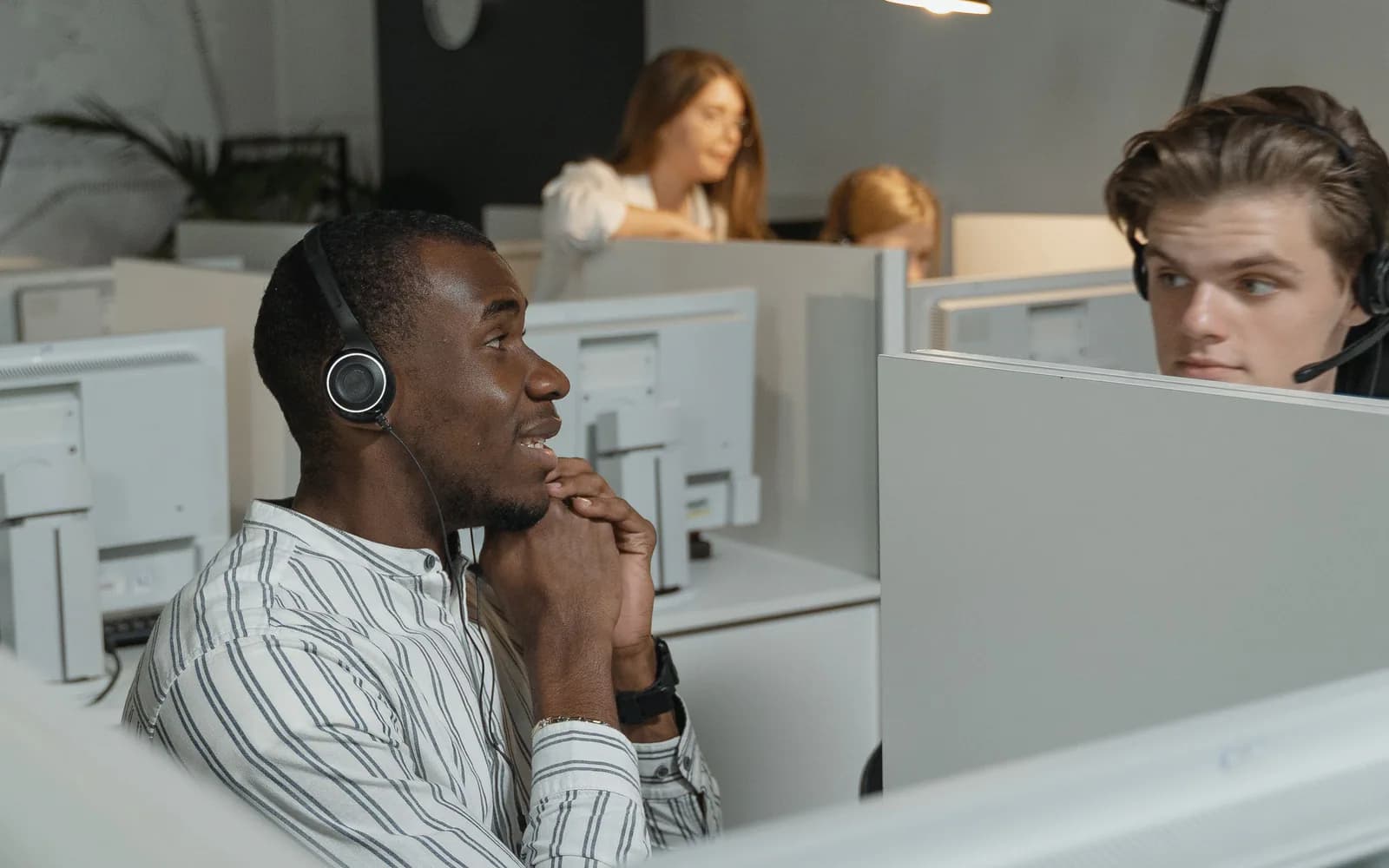A customer support team working at computer stations with headsets