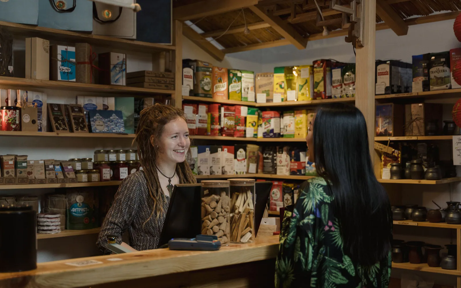 A shopkeeper assisting a customer at a stocked retail counter